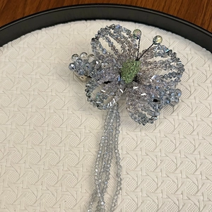 Close-up of handmade beaded butterfly hair clip with light blue crystal tassels