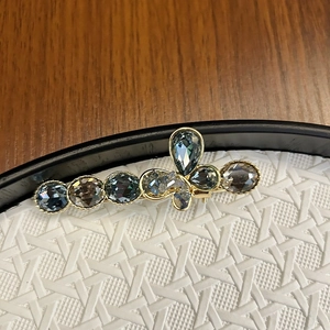 Macro shot of grey crystal butterfly hair clip with golden alloy base and faceted stones