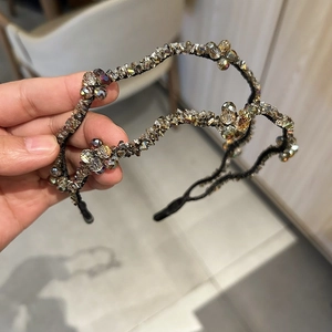Detail of wavy crystal headband featuring grey and amber stones on flexible black alloy