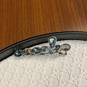 Macro shot of elegant silver metal hair clip with blue and grey teardrop crystals
