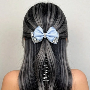Detailed view of luxury light blue satin bow hair clip with sparkling rhinestones on long hair