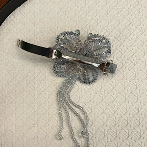 Detail view of handmade beaded bow hair clip with silver spring clasp and tassels