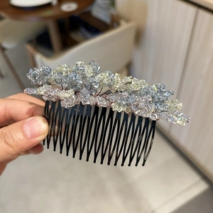 Detail view of handmade crystal hair comb with blue and purple stones and black metal teeth