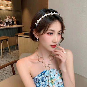 Détail d'un serre-tête floral blanc avec perles et boucles d'oreilles assorties sur modèle
