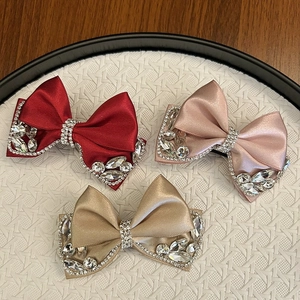 Detailed view of three satin bow hair clips with crystal rhinestones in varied colors