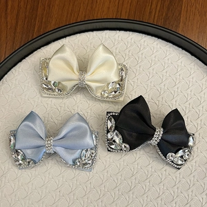 Detail view of satin bow hair clips in white blue and black with sparkling rhinestones