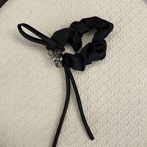 Close-up of black satin scrunchie with hand-sewn crystal beads and elegant ribbon detail