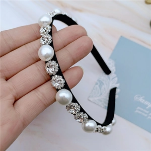 Elegant headband with white pearls and sparkling rhinestones on a black fabric frame