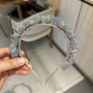 Close-up of handmade beaded headband with purple crystal cluster and pink satin base