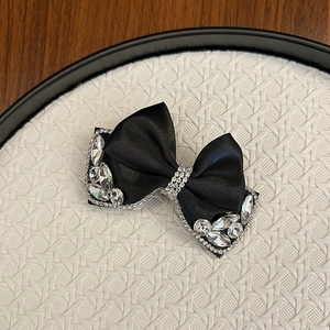 Close-up of black satin bow hair clip with luxury rhinestones and pear-shaped crystal