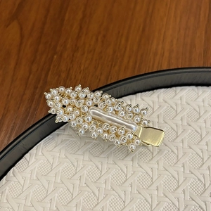 Macro shot of handcrafted white pearls and elongated crystal on a gold-tone hair clip base
