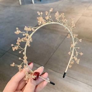 Dettaglio di perle di cristallo champagne su cerchietto a filo dorato per capelli