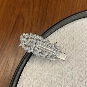 Detailed close-up of handmade faux pearl hair clip with silver metal base and crystal beads