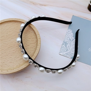 Detailed view of elegant headband with inlaid white pearls and rhinestones on black band