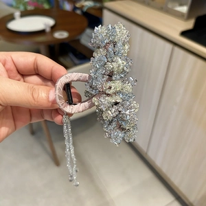 Detailed macro view of crystal hair claw clip with silk wrap and long bead tassels