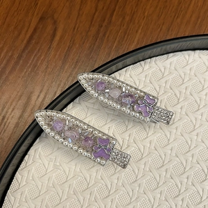 Detail of luxury handmade beaded hair clips with purple crystal bear on woven tray