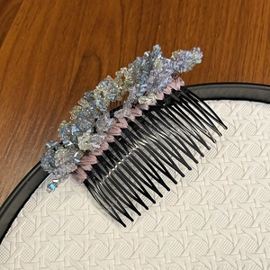 Detail of crystal hair comb with blue and purple stones on pink satin base