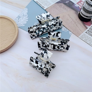Close-up of three milk-patterned acetate hair claws set with elegant marble texture