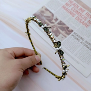 Close-up of vintage gold headband with sparkling rhinestones, pearls and dragonfly details