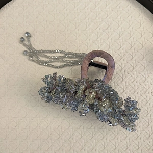 Detail of handmade hair claw clip with purple satin and iridescent crystal tassels