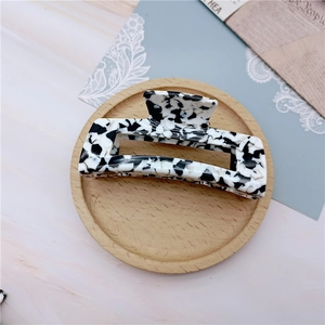 Detail shot of rectangular black and white marble pattern hair claw clip on wooden tray