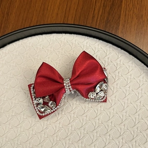 Close-up detail of luxury red satin bow hair clip with sparkling rhinestone edges
