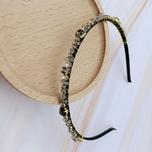Detail of slim black headband featuring cross-wrapped gold wire and grey crystal beads