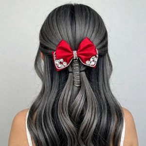 Elegant red satin bow hair clip with sparkling rhinestones on long wavy grey hair