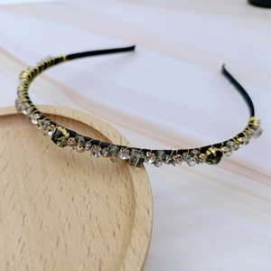 Detail of handmade headband with green crystals and gold wire on a wooden tray