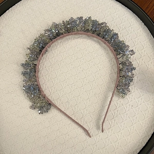 Detail of handmade crystal headband with blue and yellow gems on pink fabric