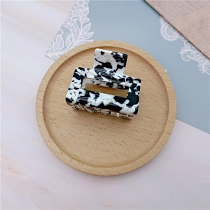 Macro detail of rectangle milk pattern acetate hair claw on a decorative wooden tray