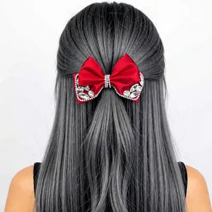 Close-up of red velvet bow hair clip with sparkling rhinestones on grey hair