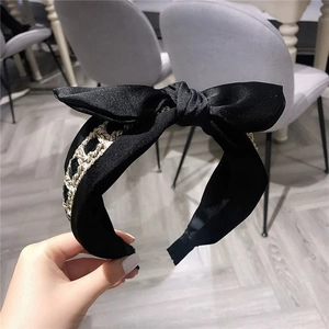 Elegant black satin headband with oversized bow and tricolor metallic woven chain detail