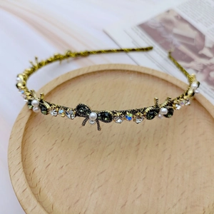 Detailed macro view of vintage gold headband with emerald gems and white pearls