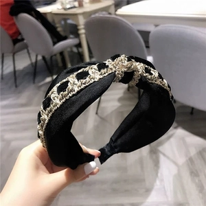 Detail of black velvet headband featuring a gold metal chain weave and twisted knot design