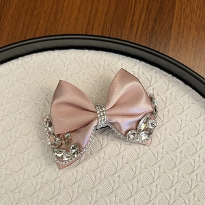 Detailed view of luxury pink satin bow hair clip with sparkling rhinestones and crystals