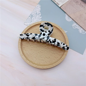 Close-up of black and white marble acetate hair claw clip on a wooden tray decor