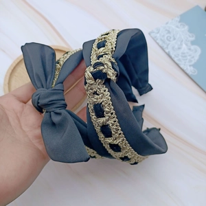 Detail of vintage navy blue bow headband featuring intricate gold crochet lace trim