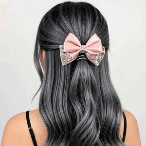 Detail of pink satin bow hair clip with sparkling rhinestones worn on a half-up hairstyle