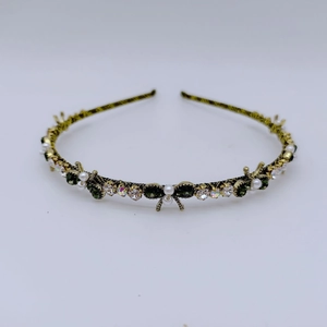 Detailed close-up of retro gold headband with green stones, pearls and rhinestones