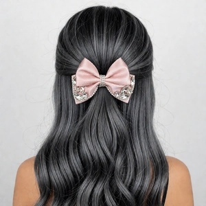 Close-up of pink satin bow hair clip with sparkling rhinestones on long wavy hair