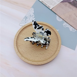 Detail of elegant black and white marble acetate hair claw clip on wooden base