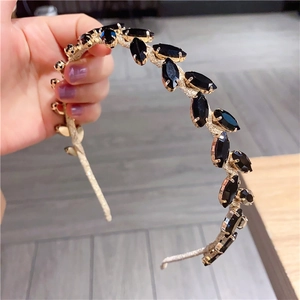 Close-up of golden metal headband featuring marquise cut black crystals in a leaf design