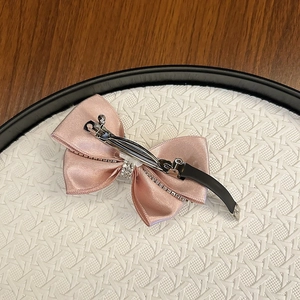 Detail of pink satin bow hair clip with rhinestone edges and sturdy metal spring back