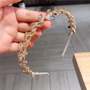 Detail of golden metal headband featuring champagne leaf-shaped rhinestones and crystals