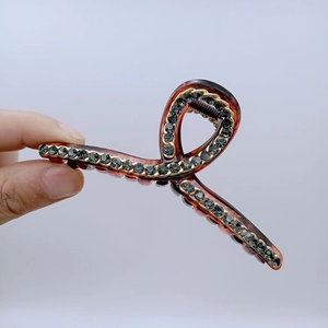 Dettaglio di grande molletta per capelli in resina marrone con strass grigi lucidi