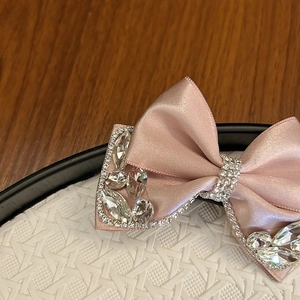 Detail of pink satin bow hair clip with large drop-shaped crystals and shimmering rhinestones