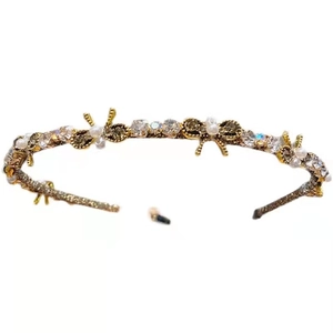 Elegant gold headband with rhinestone bows and pearls on a white background