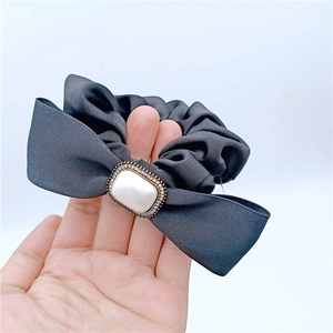 Détail d'un chouchou en soie grise avec perle rectangulaire et nœud en strass chic