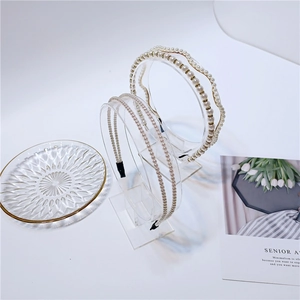 Detail view of pearl headbands in creamy white and light gold on a glass tray